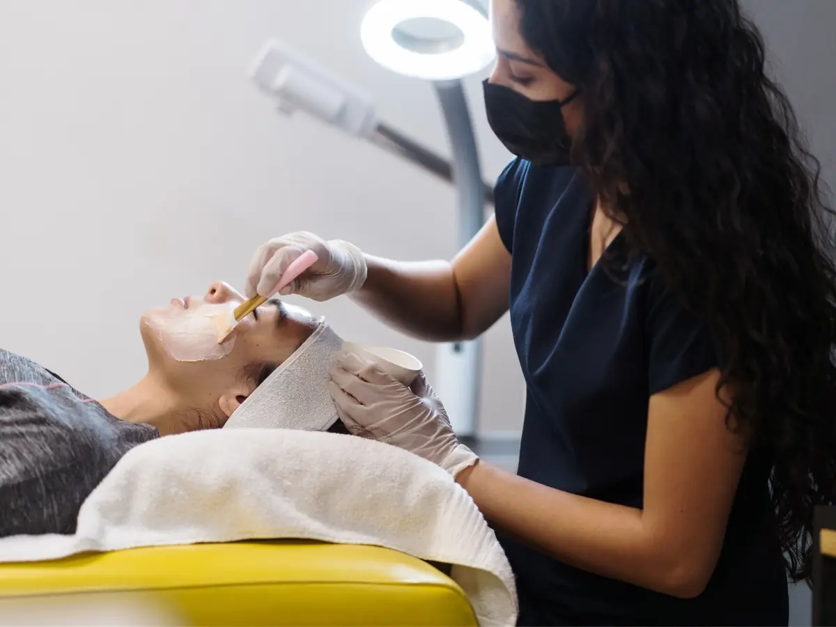 Aesthetic practitioner applying a facial mask treatment to a relaxed client
